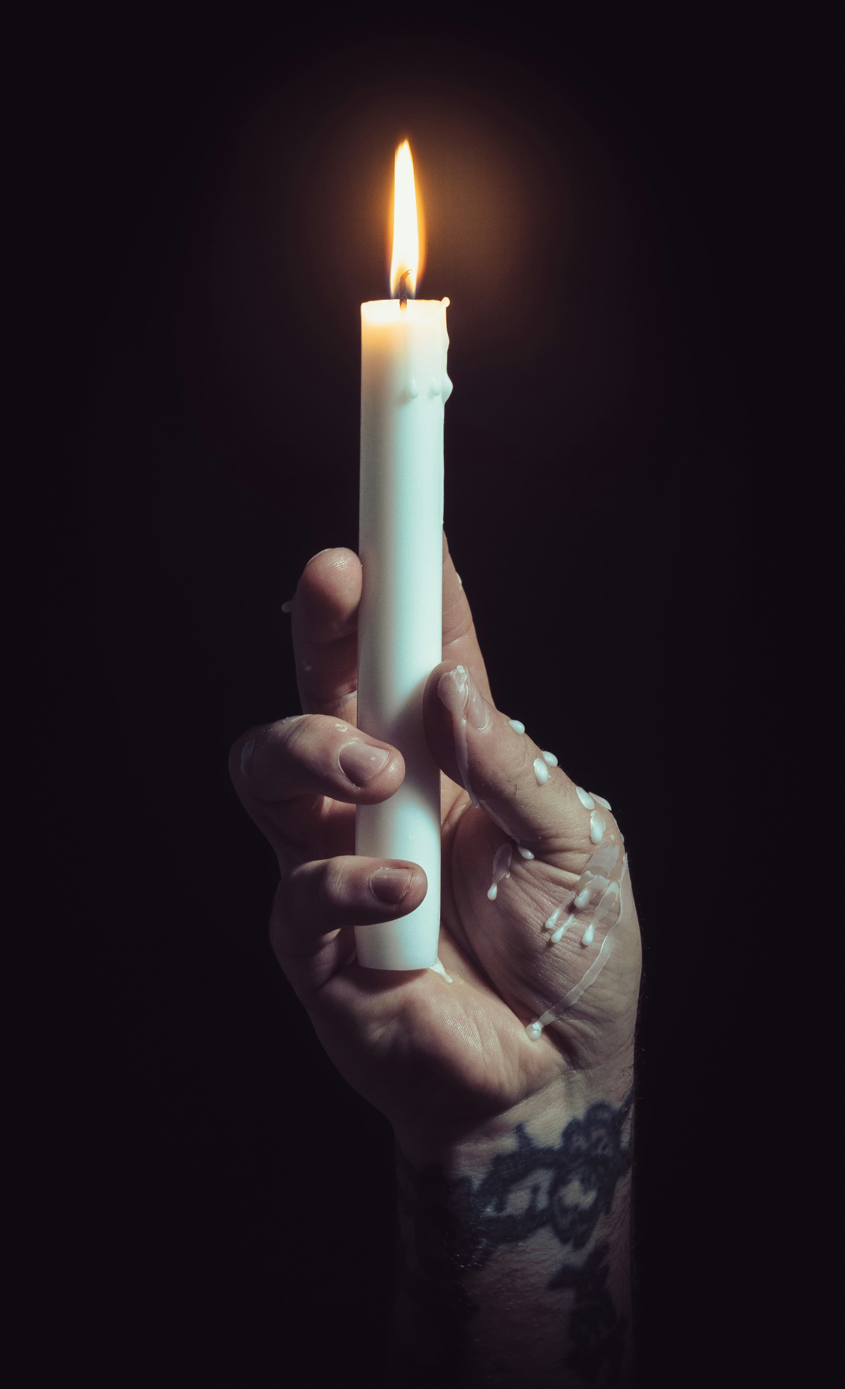 A lit hand-poured candle held in a person's hand.