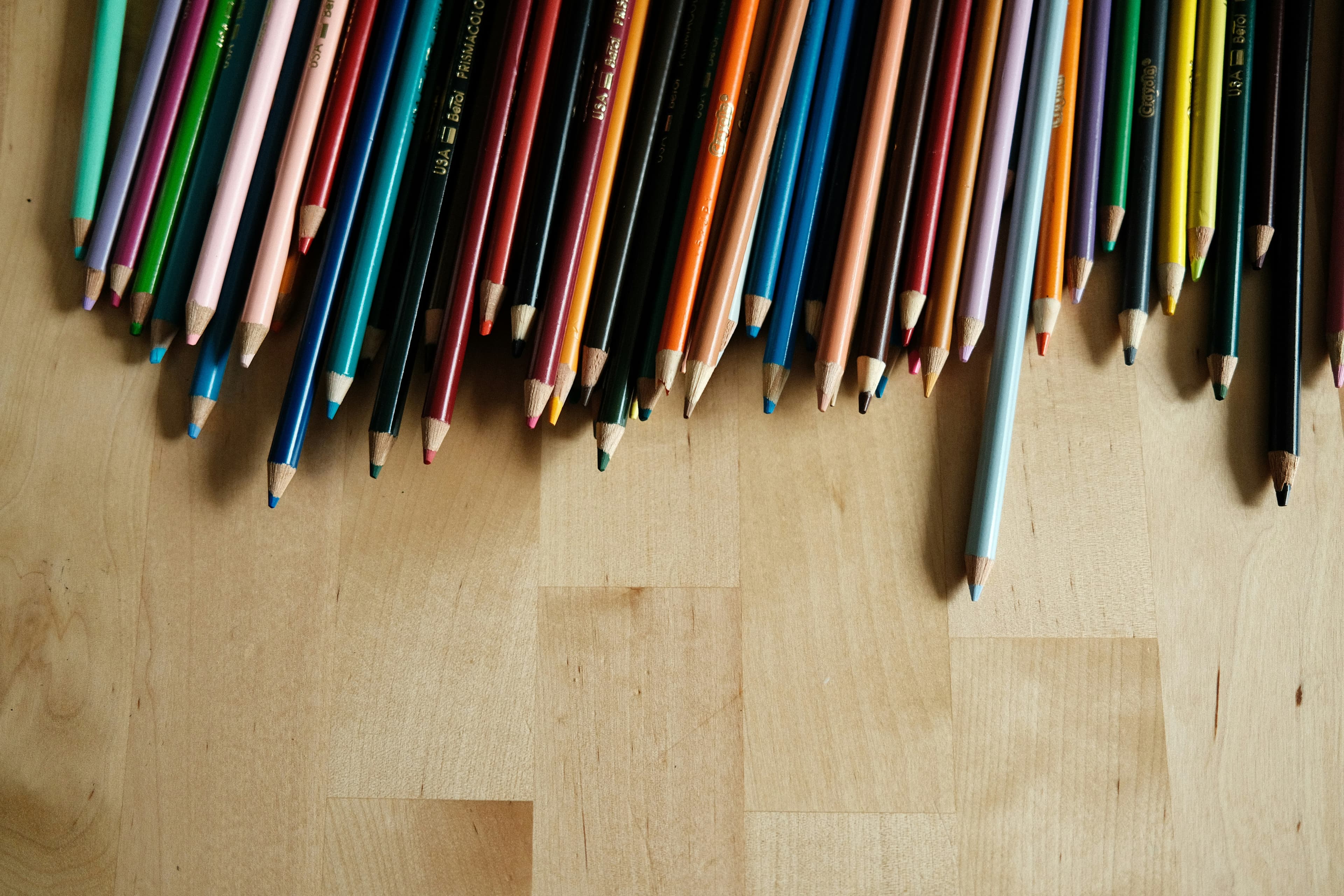 Colourful pencils arranged on a wooden surface.